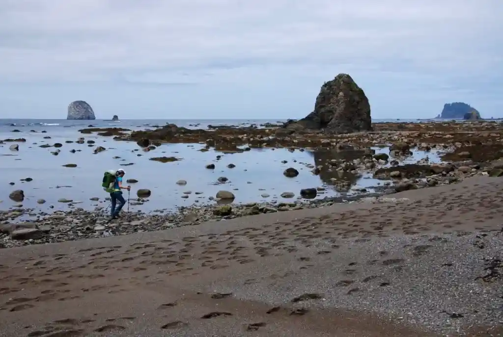 A hiker walks along the beach on the North Coast route in Olympic National Park near Cape Alava.