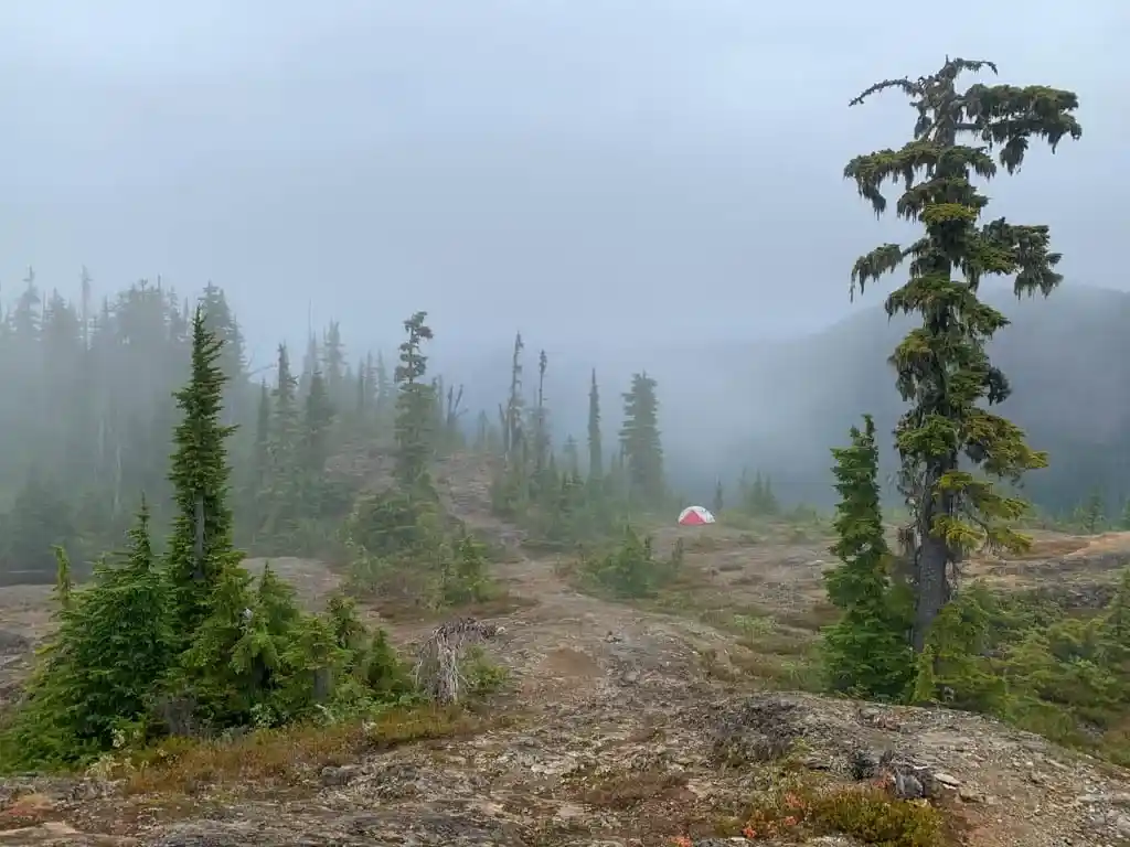 A tent in the fog on a ridge.