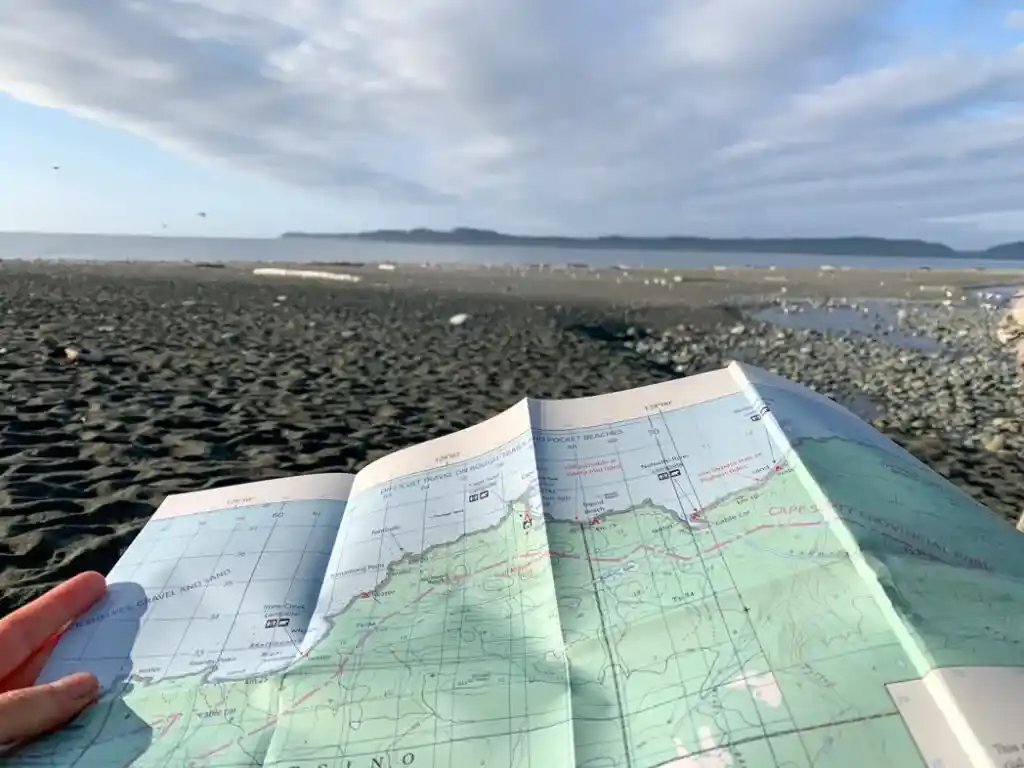 A hiker hold a map on a beach hike - A map is one of the 10 essentials you should bring on every hike and it's helpful for trip planning