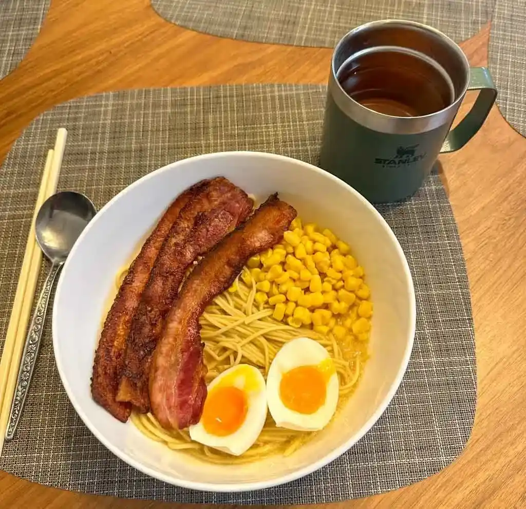 A Stanley camp mug next to a bowl of homemade ramen