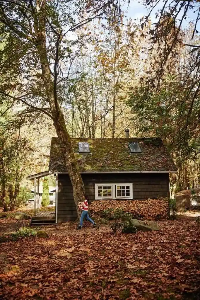 A woman walks past a wood pile at Sunwolf Riverside Cabins in Squamish